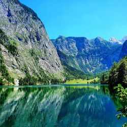 Scenic view of lake and mountains against blue sky