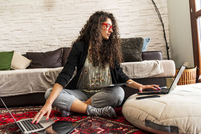 Young woman using mobile phone while sitting on sofa at home