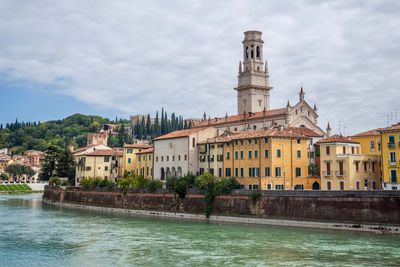 Buildings at waterfront against cloudy sky