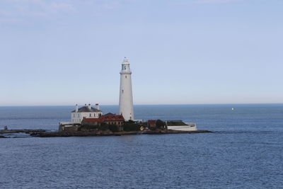 Lighthouse by sea against sky