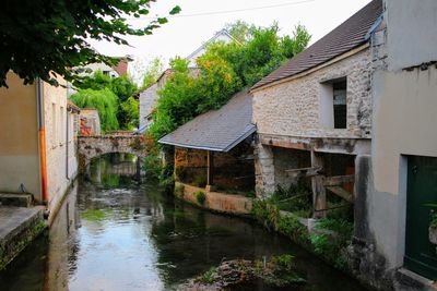 Canal amidst old buildings against sky