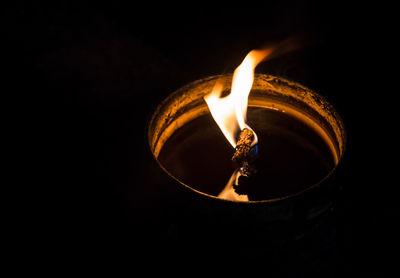 Close-up of lit candle against black background