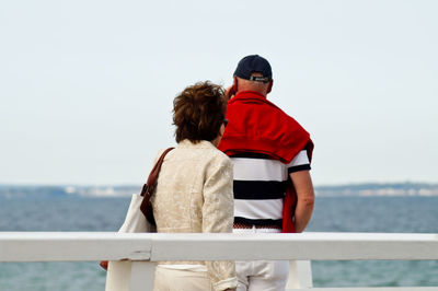 Man and woman standing at railing against sea