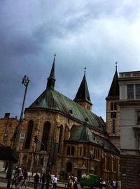 Low angle view of buildings in city against cloudy sky