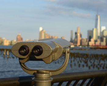 Close-up of coin-operated binoculars with buildings in backgrounds