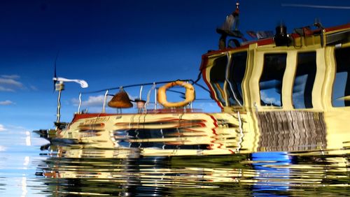 Boats moored on sea against clear blue sky