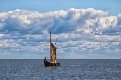 Retro wooden sailing ship sails into the sea. beautiful clouds.