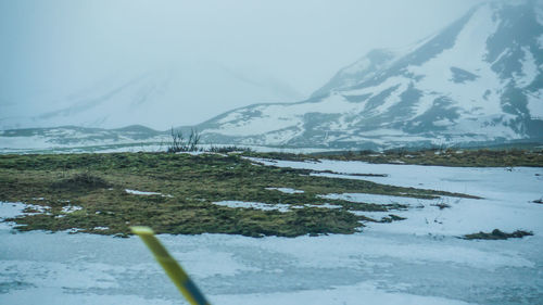 Scenic view of lake by snowcapped mountains against sky