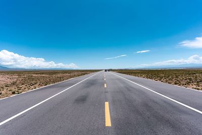 Road passing through landscape against blue sky