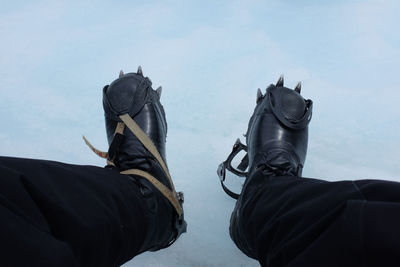 Low section of person wearing crampon shoes on snow covered field