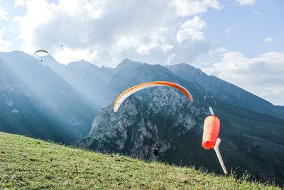 People paragliding on mountain peak against sky