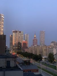 Modern buildings in city against clear sky at dusk