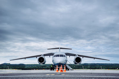 Airplane on airport runway against cloudy sky