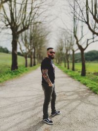 Portrait of young man standing on footpath