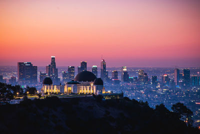 Illuminated buildings in city during sunset