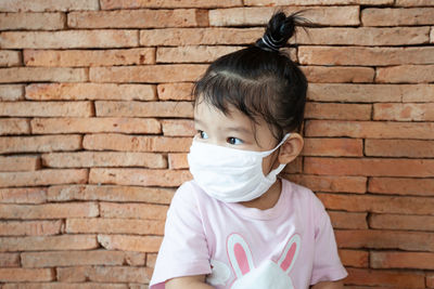 Portrait of girl against brick wall