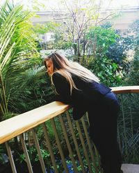 Side view of woman standing by railing against trees