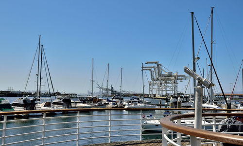 Sailboats moored at harbor against clear sky