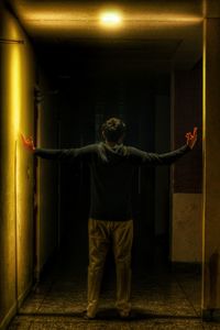 Full length of man standing against illuminated wall at night