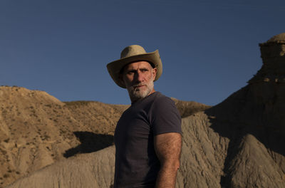 Adult man in cowboy hat on desert against mountain. almeria, spain