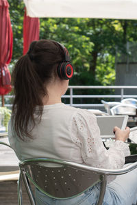 Sad girl listens to music from a tablet at a table in a cafe