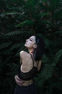 Woman looking up while standing against plants