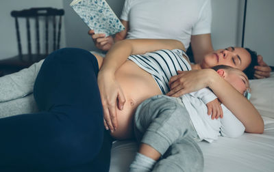 Midsection of friends relaxing on bed at home