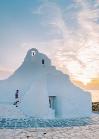 Man by building against sky during sunset