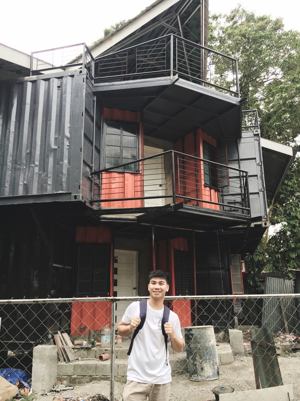 PORTRAIT OF YOUNG MAN STANDING BY BUILDING