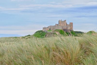 Castle on hill against cloudy sky