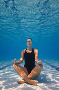 Female model meditating in pool