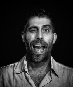 Portrait of man winking on black background