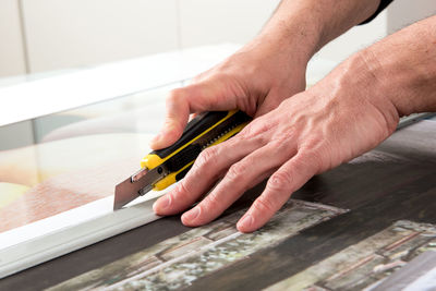 Cropped image of man using utility knife on table