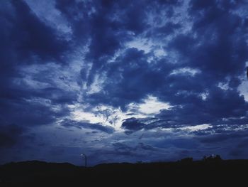 Low angle view of silhouette trees against blue sky