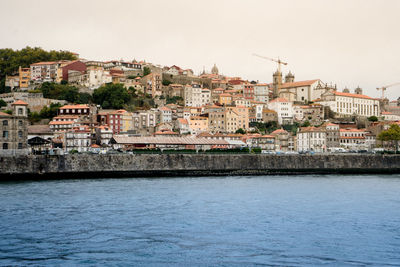 Buildings by sea against clear sky