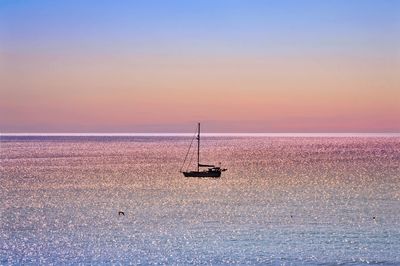 Silhouette sailboat sailing on sea against sky during sunset