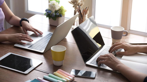 Midsection of man holding smart phone on table