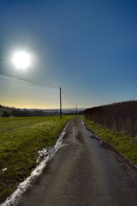 Road amidst field against clear sky