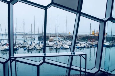 Sailboats moored on sea against sky seen through window