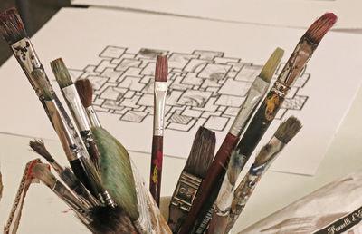 High angle view of various paint brushes by drawing at table