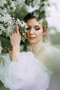 A beautiful elegant woman bride in a wedding dress walks alone in a blooming spring outdoor park