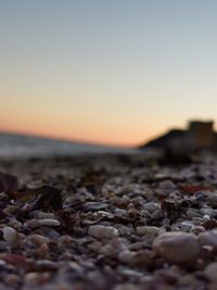 Pebbles on beach against sky during sunset