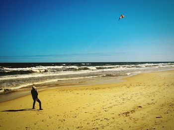 Man standing on beach against clear sky