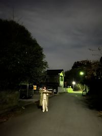 Empty road by trees against sky at night