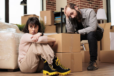 Angry couple sitting by boxes during relocation