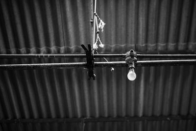 Close-up of chain hanging on rope against wall