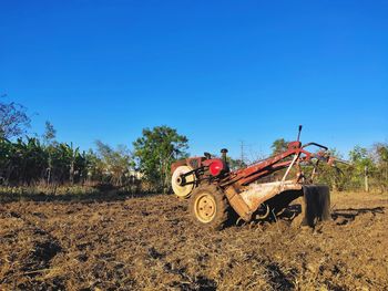 Tractor on field against clear blue sky