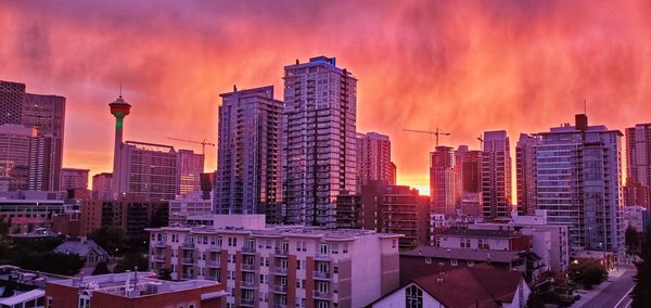 Modern buildings in city against sky during sunset