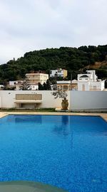 Swimming pool by building against sky