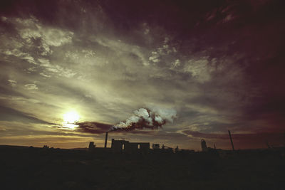 Smoke emitting from factory against sky during sunset